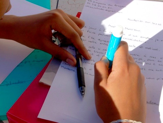 Une jeune est en train de rédiger une lettre de motivation dans le cadre d'un projet d'insertion professionnelle.